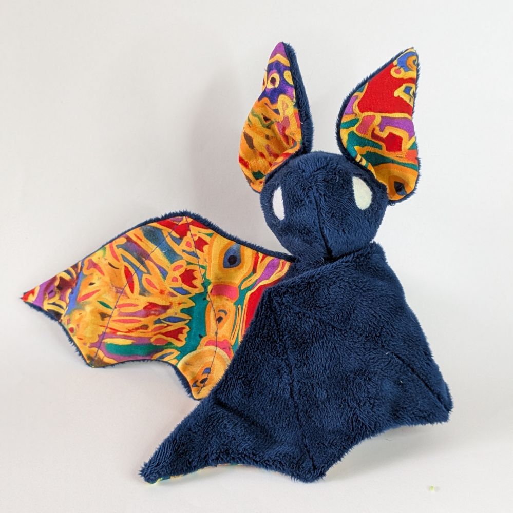 Midnight blue bat plushie with colorful abstract pattern wings and ears 