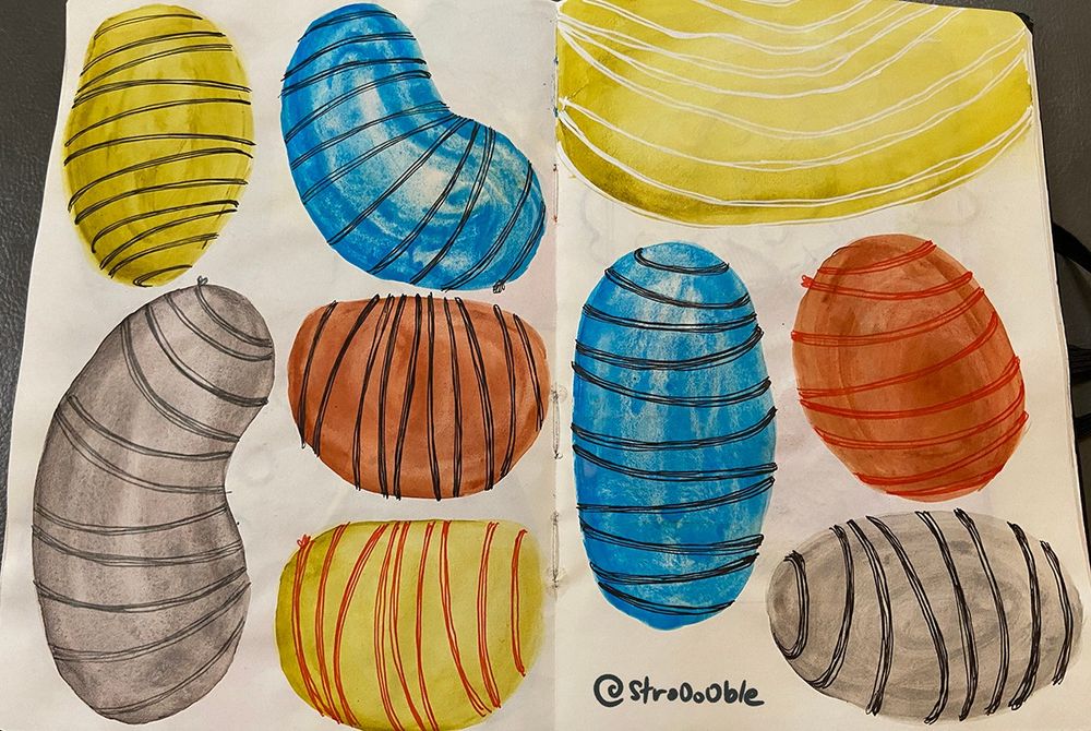 An open sketchbook showing two pages of beans in different colours, decorated with lines.