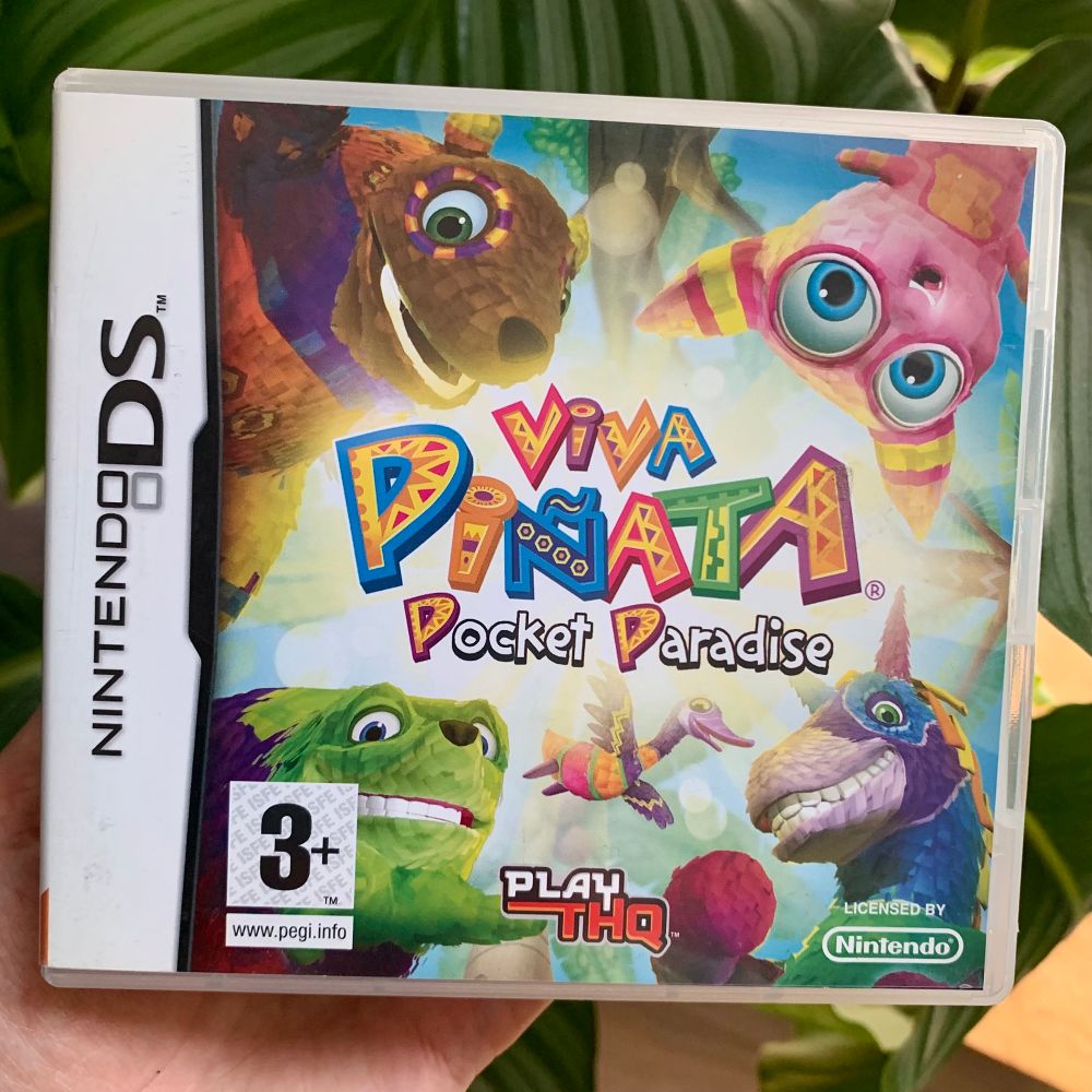 Closeup of a Viva Piñata: Pocket Paradise game box for the Nintendo DS, with a bunch of colorful piñata characters surrounding the logo in the middle.