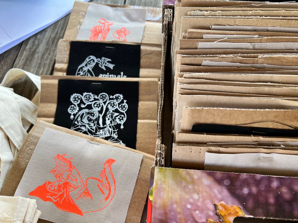 Ein ganzer Karton voller kleinerer Kartonstücke, auf denen jeweils ein Patch festgetackert ist. Die Patches haben unterschiedliche Farben und zeigen verschiedene mittelalterliche Figuren.