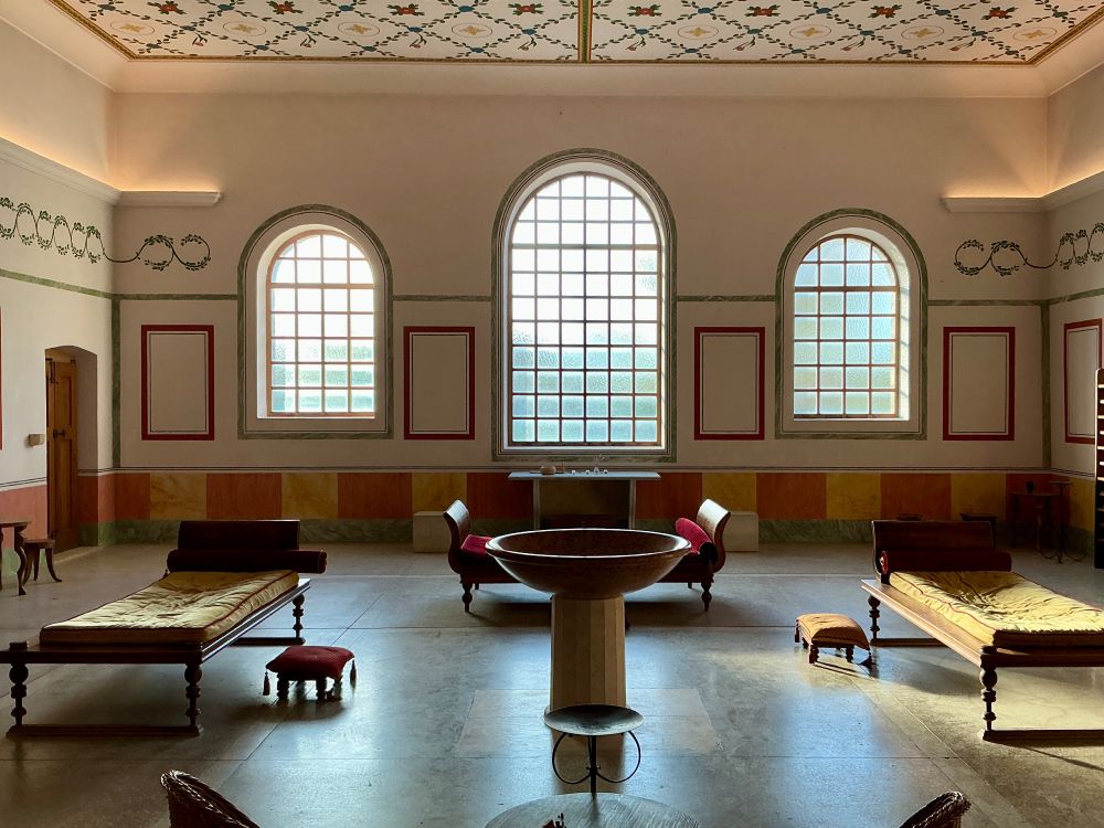 Aufenthaltsraum der Römischen Therme in Carnuntum mit Relaxmöbeln und wunderschönen Wandmalereien. Seitlich an den Wänden wurde wohl eine sehr dezente, aber doch ins Auge fallende elektrische Beleuchtung installiert.