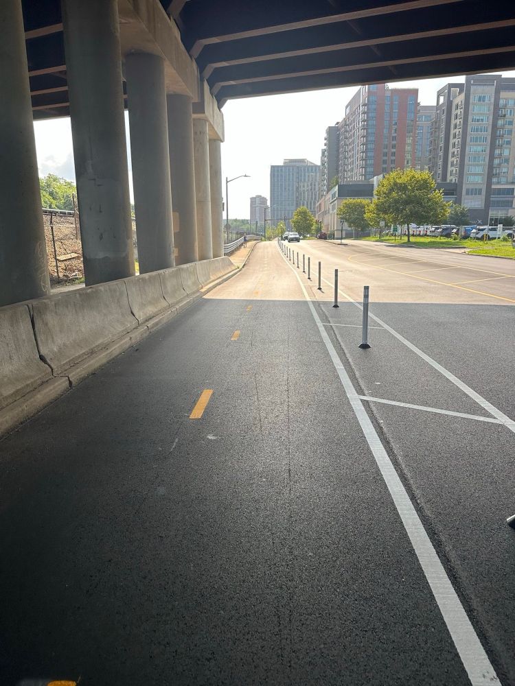 A short stretch of new bidirectional bike lanes protected by flexiposts under a bridge. 