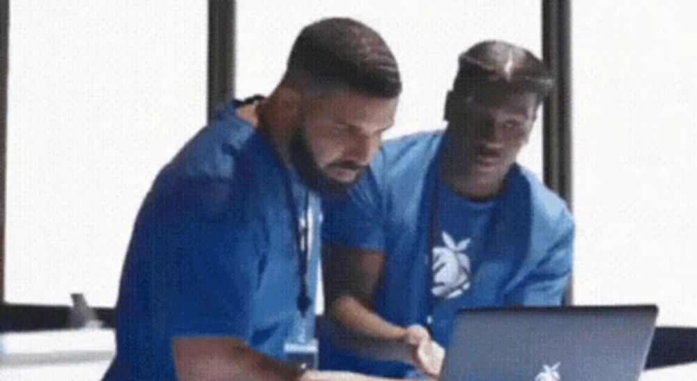 two men are looking at a laptop together .