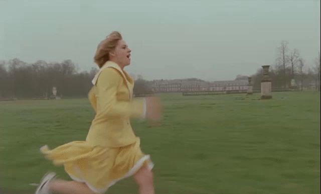 a woman in a yellow dress is running through a grassy field .