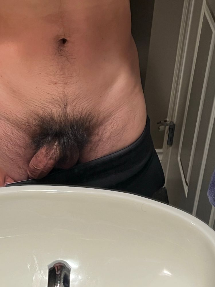 Me pulling my pants down to expose my bush and base of my cock in front of the mirror