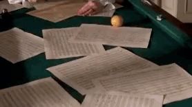 a person is sitting at a table with a bunch of papers and a lemon on it .