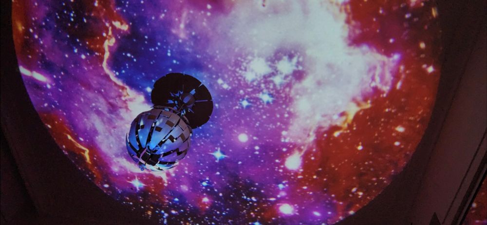 A colourful galaxy projection over a round lampshade and roof.