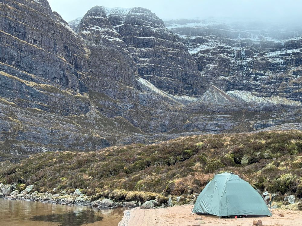 Tent pitched with mountain backdrop.