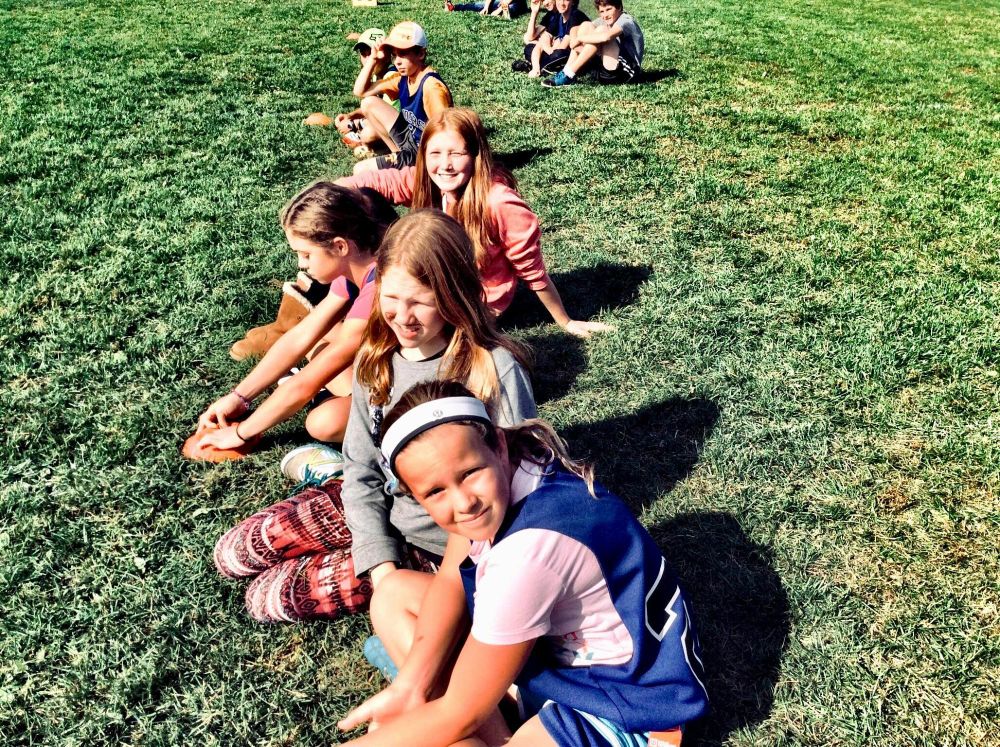 young children lined up in a row on the grass on a sunny day