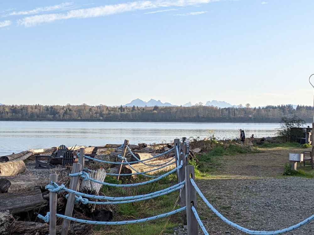View of the N cascade mountains in the distance with a driftwood rocky beach and inlet bay