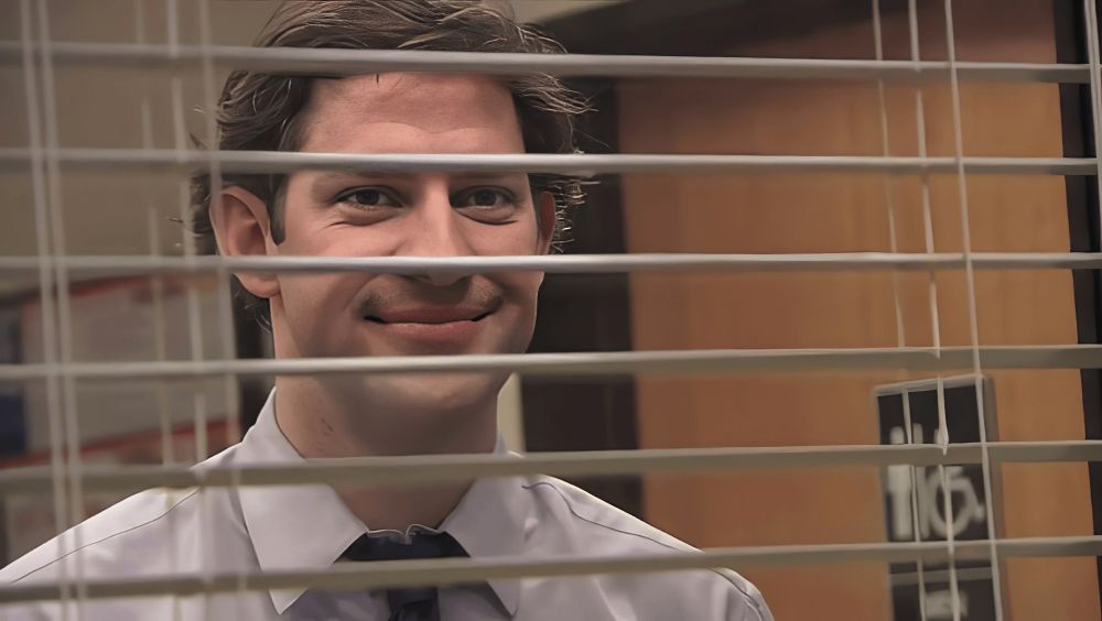 Jim Halpert from the Office smugly watching through blinds