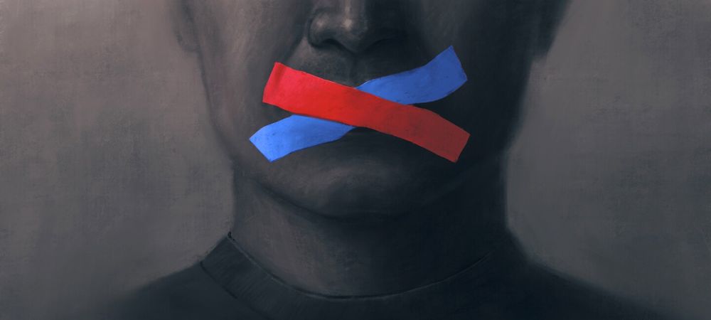An image metaphorically depicting political attacks on academic freedom by showing a man's mouth taped shut with blue and red tape.