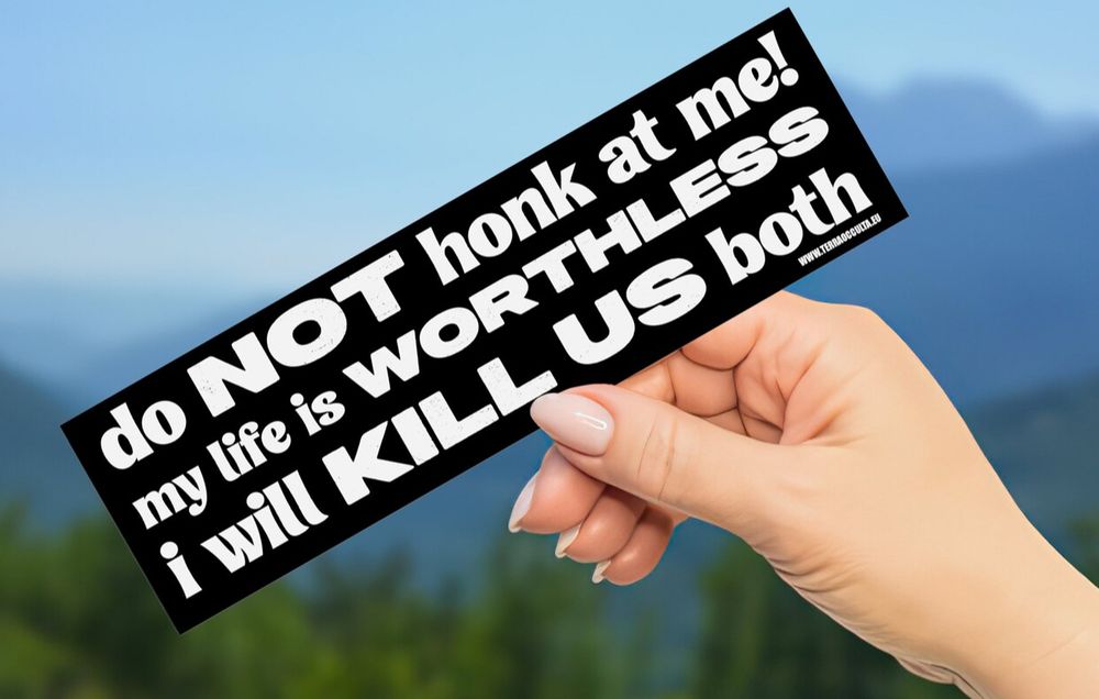 A hand holding a bumper sticker that reads “do NOT honk at me! my life is WORTHLESS. I will KILL US both.”