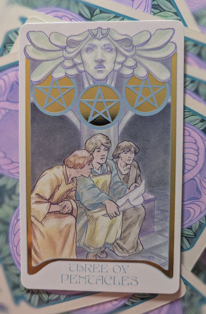 Three of Pentacles from the features three people reading a big sheet of paper and there are three golden pentacles above them.