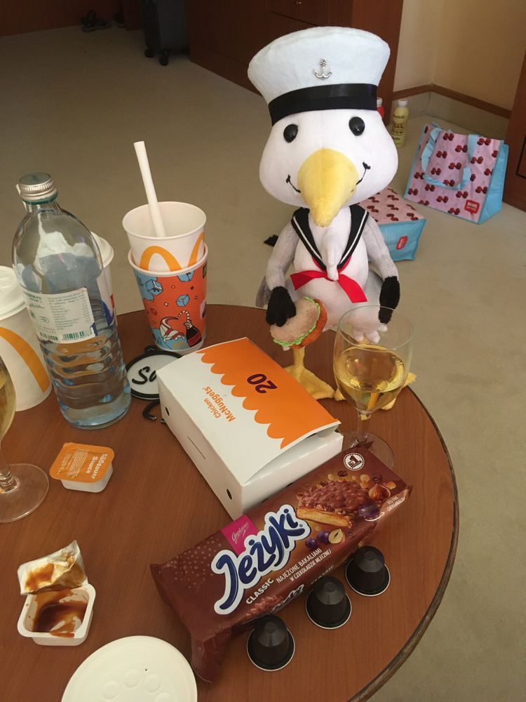 An anthropomorphic plush seagull in front of a table full of food containers
