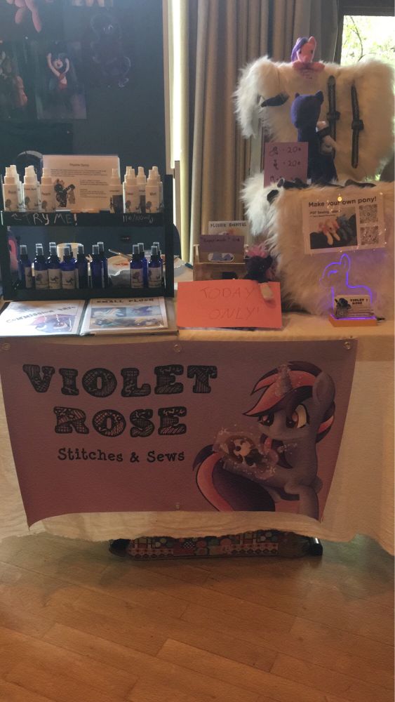 Vendor table, featuring fursuit spray and a few plushie accessories