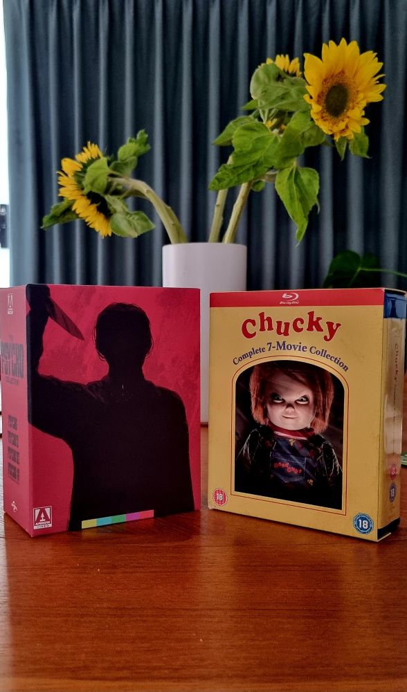 A photo of my kitchen table with two bluray box sets on top: Psycho (1-4) and Child's Play (1-7).