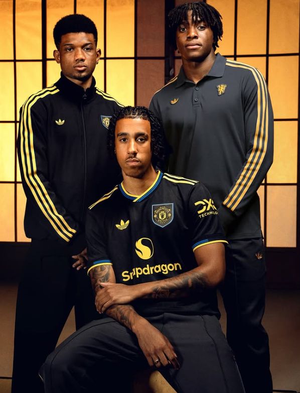 Foto de três jogadores do Manchester United; Amad, Yoro e Dorgu. Yoro usa o novo terceiro uniforme do time, e os demais usam uma camiseta polo e o outro uma jaqueta do uniforme. Todo o uniforme é todo preto, da marca adidas, com detalhes da camisa e do escudo em amarelo, e alguns contornos na manga e gola em azul-escuro.
