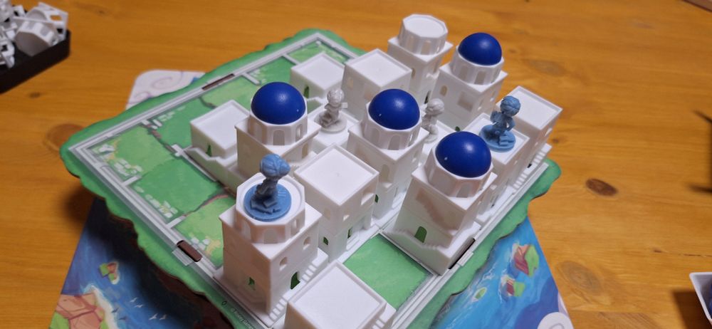 Santorini Spielfeld mit Gebäuden und Figuren.