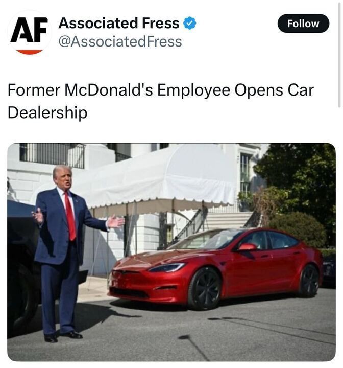 X post by Associated Press (@AssociatedFress
), featuring a verification badge and a "Follow" button. The text of the post reads, "Former McDonald’s Employee Opens Car Dealership." The attached image shows a person in a blue suit with a red tie standing with arms outstretched in front of a red Tesla car parked on a driveway. In the background, there is a white building with columns, partially covered by a white canopy, and some greenery. The scene appears to be staged humorously, suggesting a connection to the White House or a similar official building.