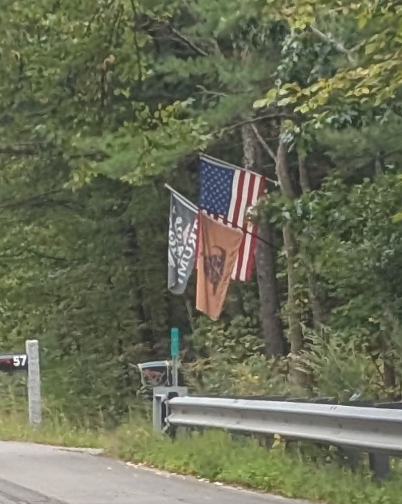 A faded Trump 2024 and "Don't tread on me" flag hang limply next to the Stars and Stripes outside a home in New Hampshire.