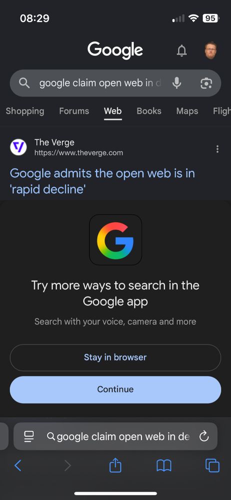 An image of a Google search page on an iphone. The search is for "google claim open web in d[ecline]". Below, the very first search result, The Verge's article on this, peeks out above a big banner, over half the screen in height, reading

Try more ways to search in the Google app
Search with your voice, camera and more
A "Stay in browser" button is visually deëmphasised
A "Continue" button is a bright colour and emphasised

The banner covers all the rest of the results, and only leaves the headline of the first result visible.
