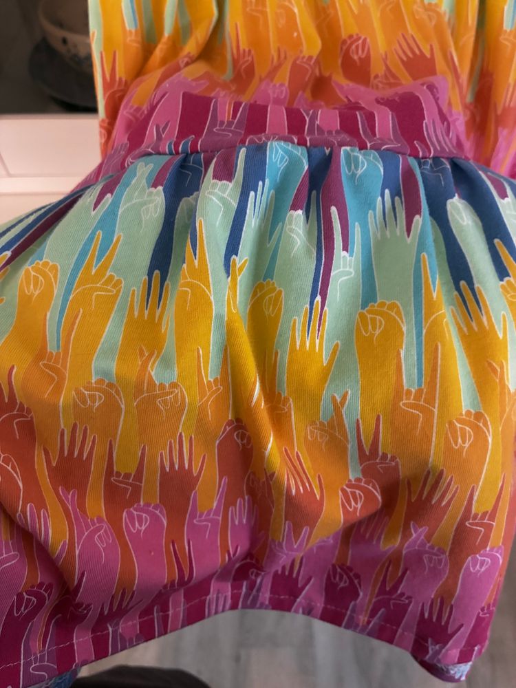  Close up of pattern upraised hands in rainbow ombre making signs like peace, resistance, love