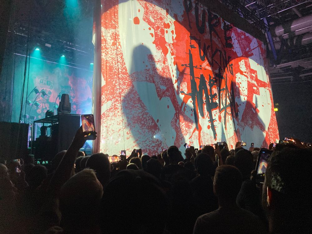 Shortly before the start, a huge sheet with “pure fucking metal” covered the view on the stage. Due to light from behind, the silhouettes of two members of the band are visible as shadows. 