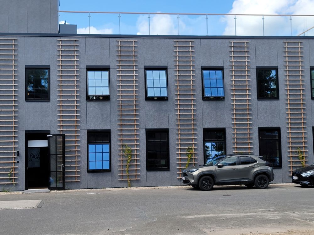 A danish two story building with at least five ladder like trellises going from the ground to the roof. 