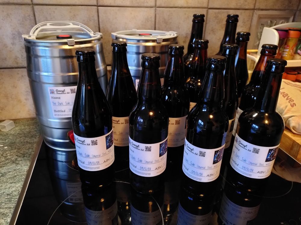 Two mini kegs and a set of bottles on a kitchen top. They contain a homebrew and the labels on the bottles indicate it is an Imperial Stout. 