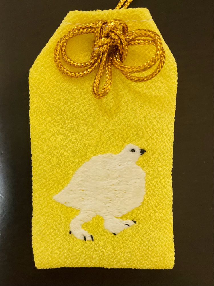 黄色の地に白いライチョウを刺繍した手作りお守りの写真