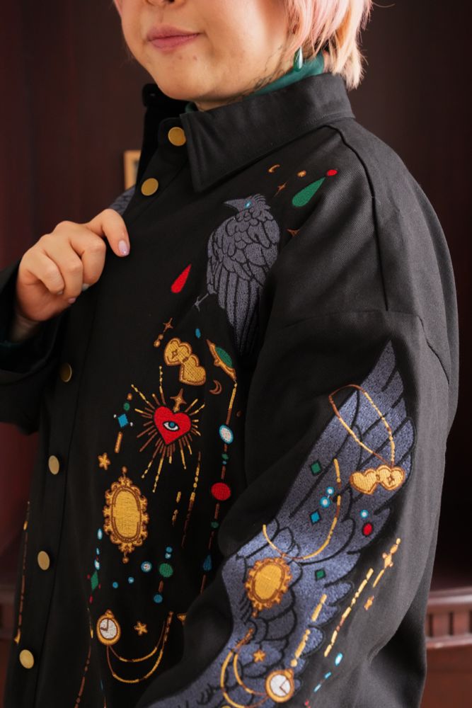 Model wearing black jacket with jewels and crow wing shaped embroideries. 
