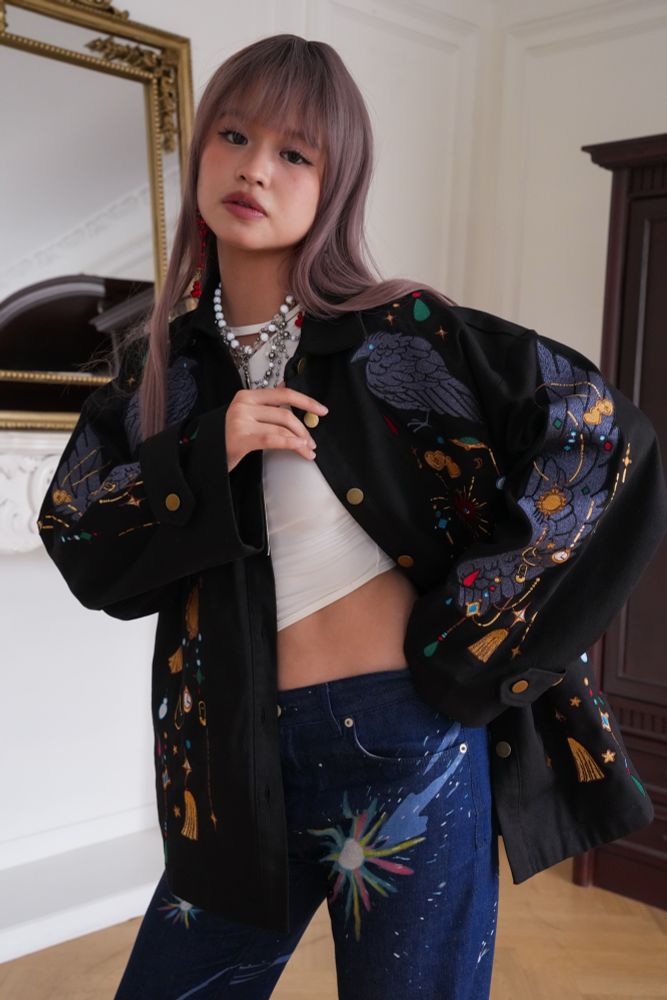 Model wearing black jacket with jewels and crow wing shaped embroideries. 

