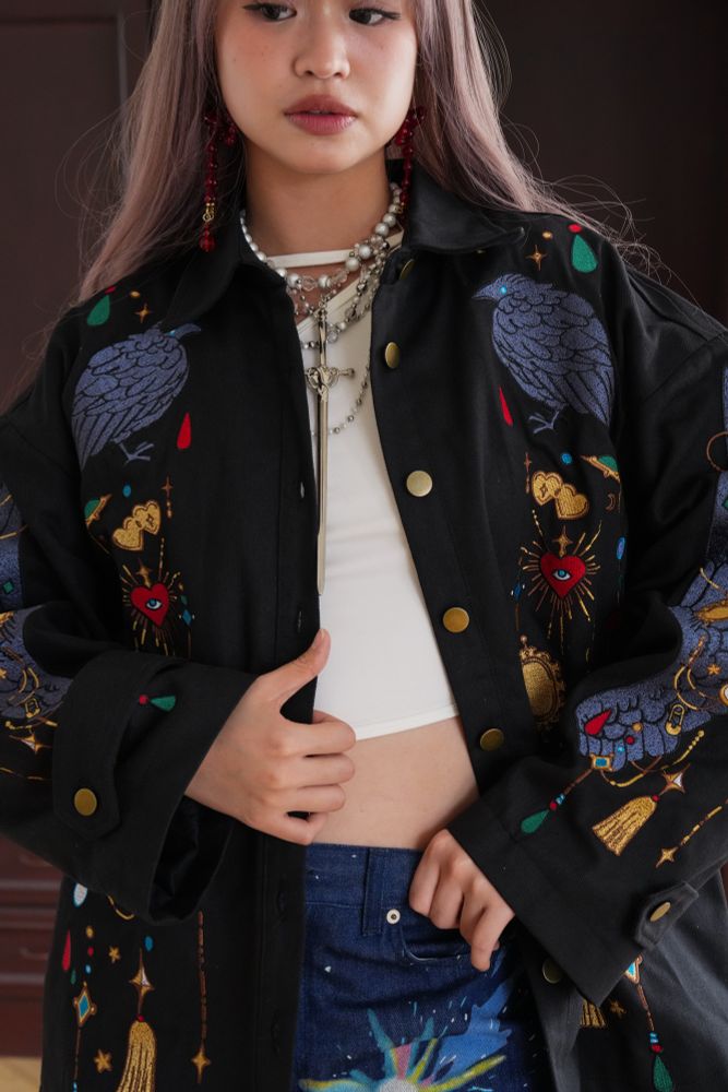 Model wearing black jacket with colorful jewelry shaped embroideries. 