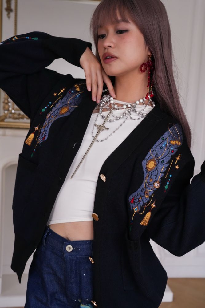 Model wearing black cardigan with jewels and crow wing shaped embroideries. 
