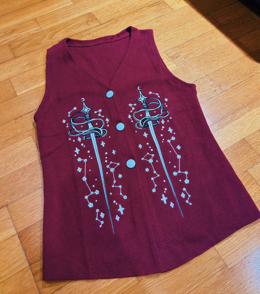 Burgundy knit sweater vest with sword shaped embroideries. 