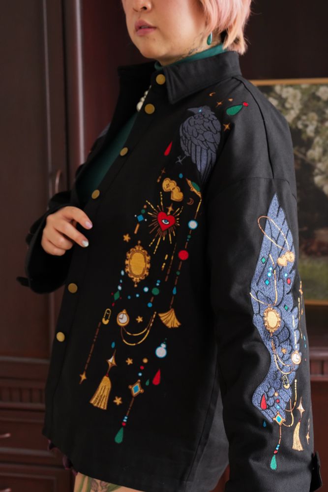 Model wearing black jacket with jewels and crow wing shaped embroideries. 
