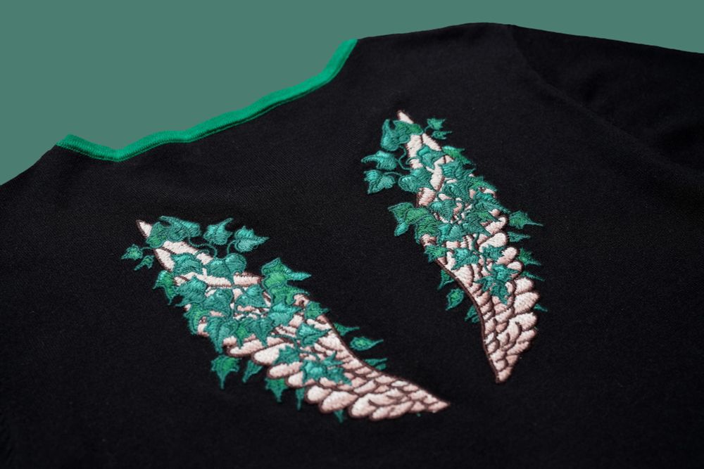 Close up of embroidered angel wing covered with ivy plants.
