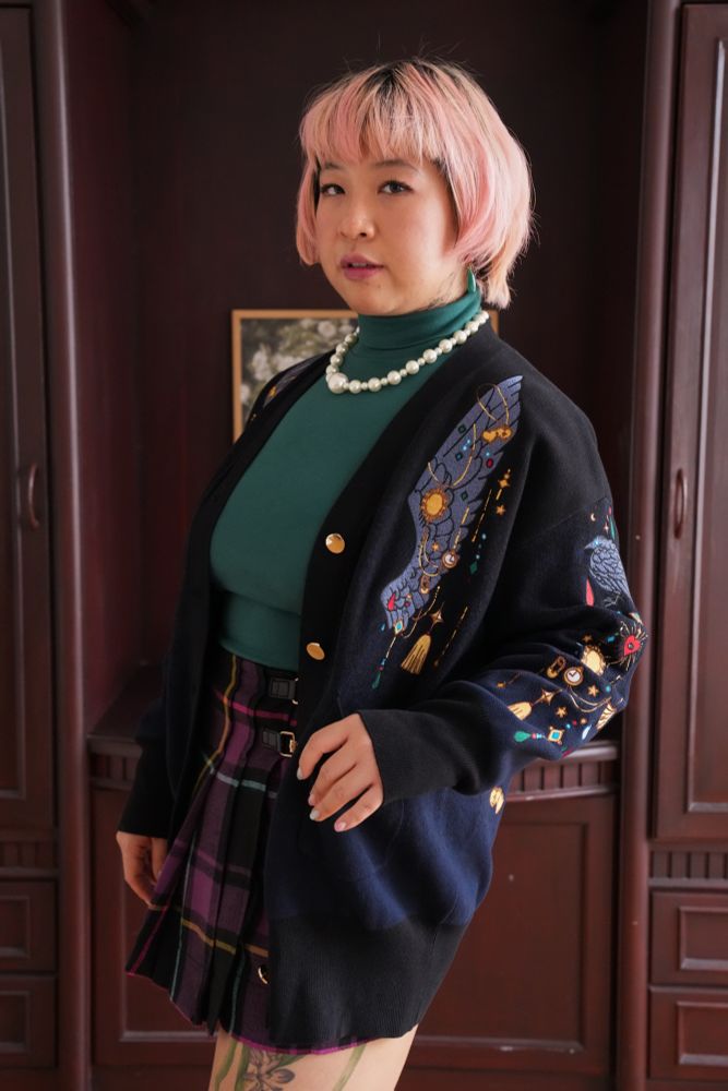 Model wearing black cardigan with jewels and crow wing shaped embroideries. 

