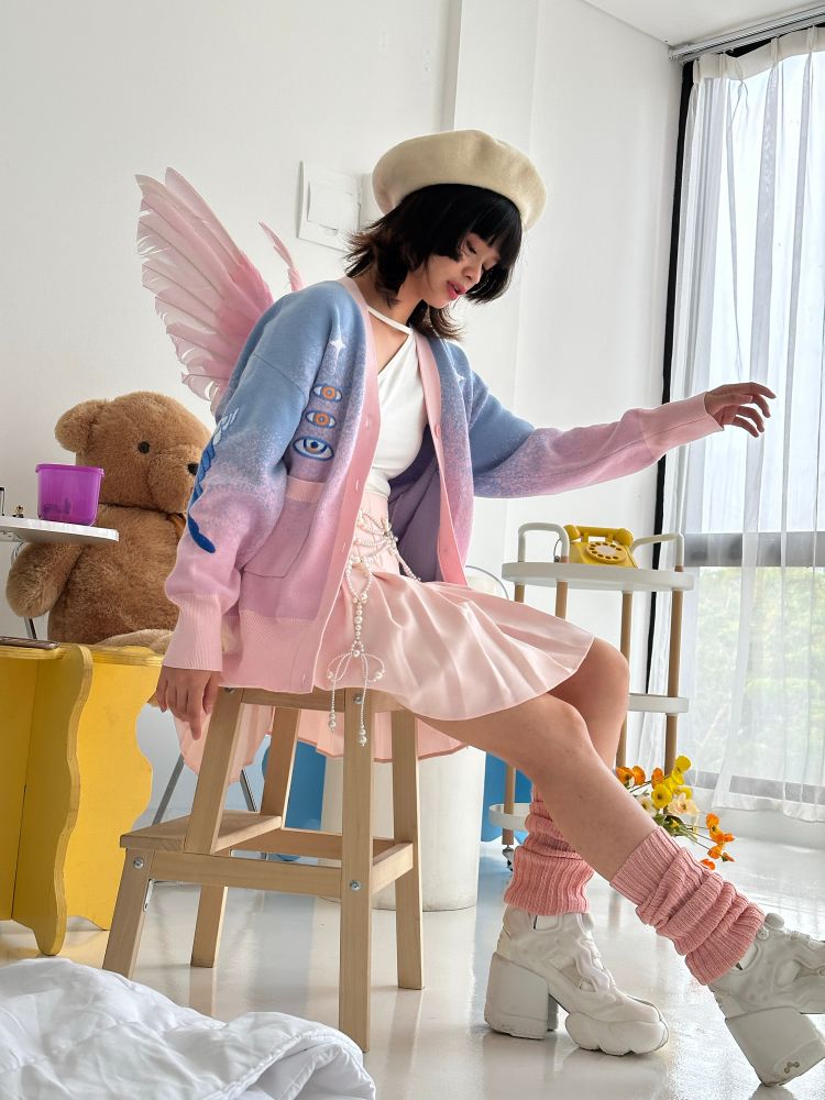 Model wearing blue and pink gradient knit cardigan with blue eyes and wings embroideries.