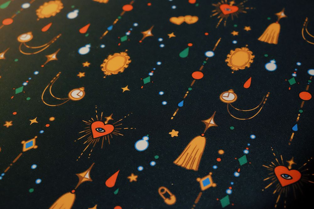 Close up of a black desk mat with jewels, trinkets, and crow print
