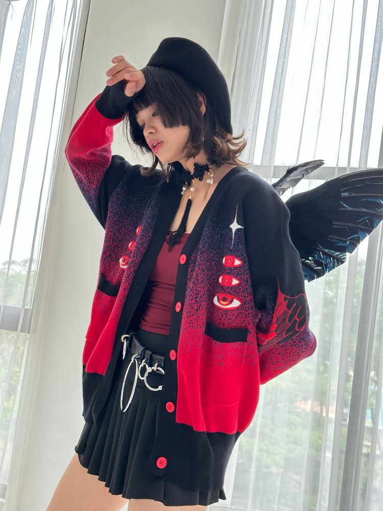 Model wearing black and red gradient knit cardigan with red eyes and wings embroideries.