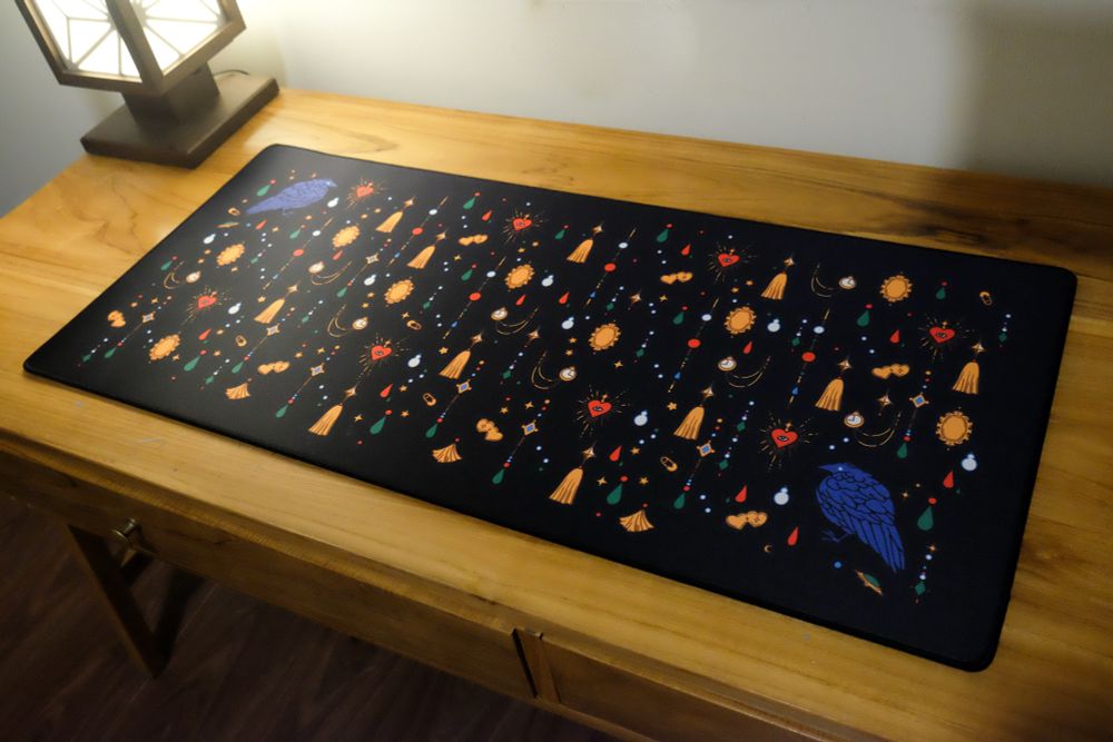 Photo of a black desk mat with jewels, trinkets, and crow print