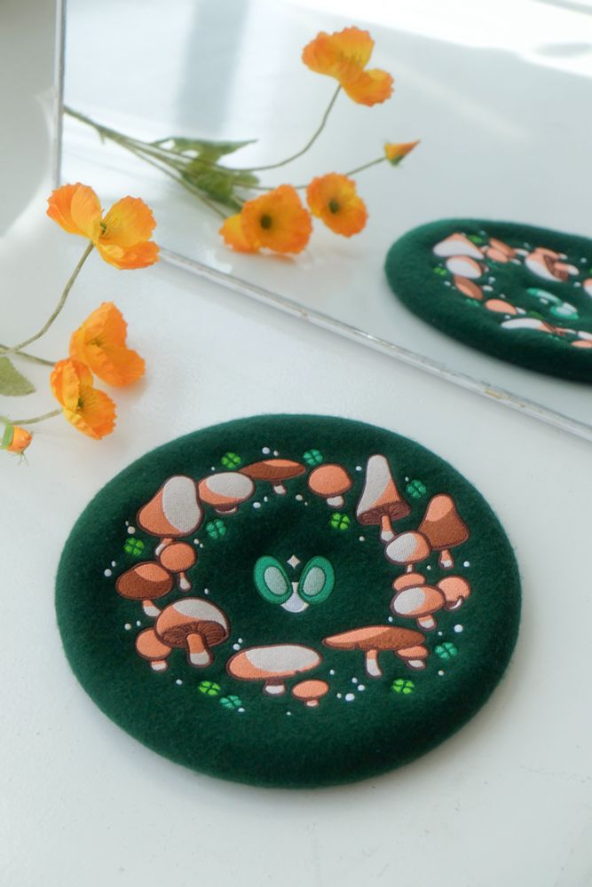 A green felt beret with embroidered fairy ring on it. 