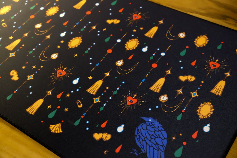 Close up photo of a black desk mat with jewels and crow print