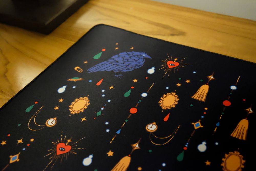Photo of a black desk mat with jewels and crow print