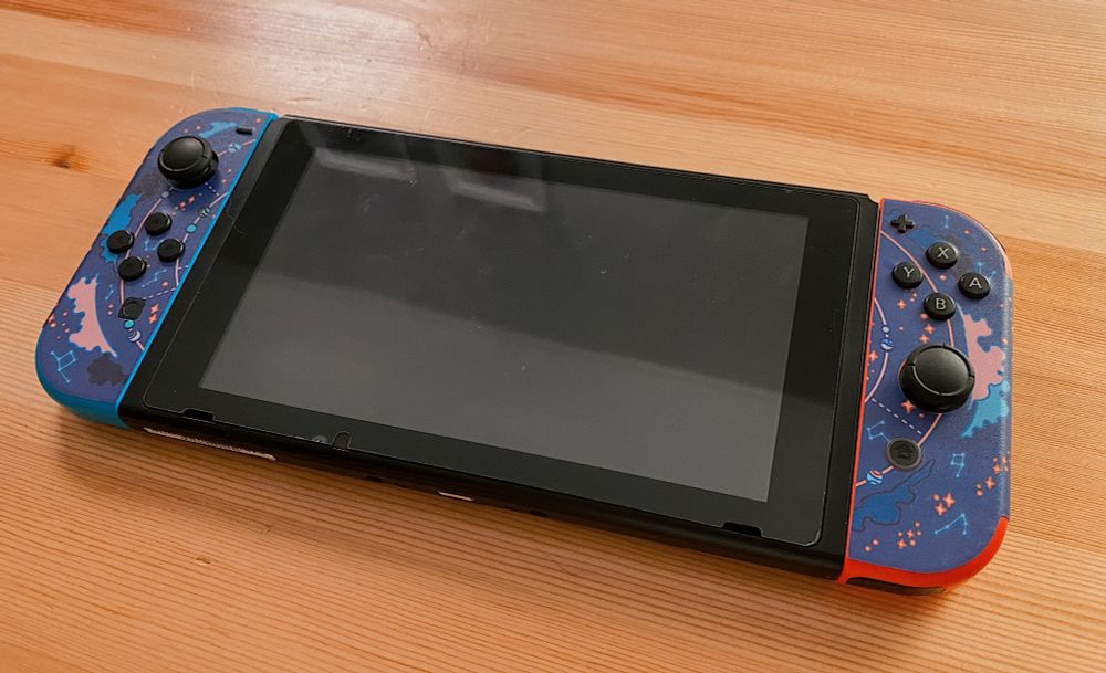 Switch console back covered with blue decals with artwork of stars, planets, and nebulae