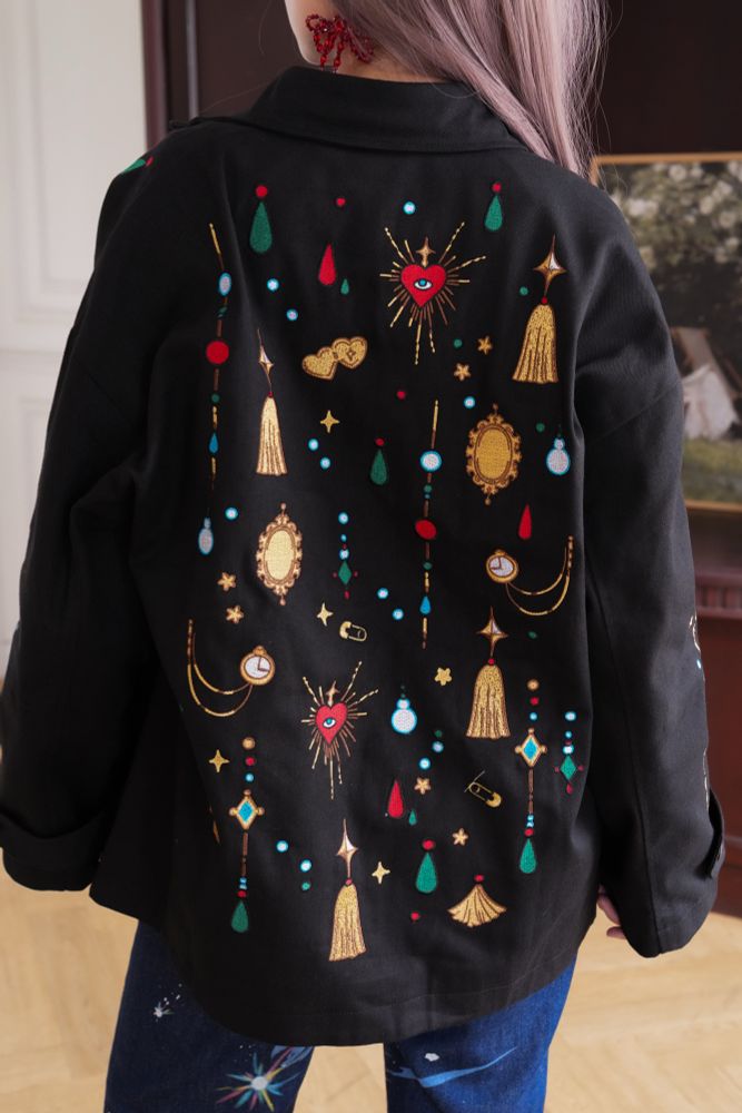 Model wearing black jacket with jewels shaped embroideries on the back. 