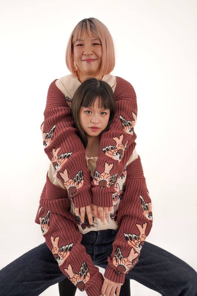 Two models wearing brown rib knit bolero with sparrow embroideries on the sleeves. 
