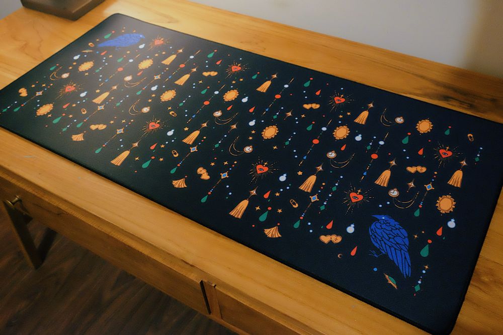 Black desk mat with jewels and crow print. 